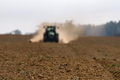 A farmer sowing in the background with a John Deere tractor and a Horsch Pronto 4dc seeding machine.-stock-photo