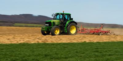 A farmer is plowing with a John Deere tractor. Sunny day on the field. It's a panning shot, that cause the blurry background and foreground.-stock-foto