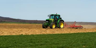 A farmer is plowing with a John Deere tractor. Sunny day on the field. It's a panning shot, that cause the blurry background and foreground.-stock-foto
