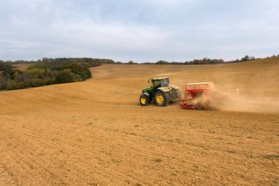 A farmer sowing with a John Deere tractor and a Horsch Pronto 4dc seeding machine. It's a panning shot, that cause the blurry background.-stock-foto