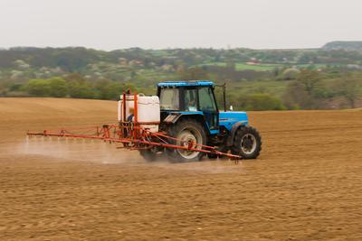 A farmer spraying with a Landini Evolution 9880 tractor. It's a panning shot, that's cause the blurry in the back and foreground.-stock-foto