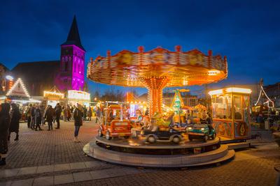 08.12.2024: Blick auf den Weihnachtsmarkt in Pasewalk mit Kinderkarussell. Im Hintergrund wird die St. Marienkirche lila-stock-foto