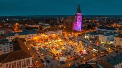 08.12.2024: Blick auf den Weihnachtsmarkt in Pasewalk. Im Hintergrund wird die St. Marienkirche lila angestrahlt Pasewal-stock-foto