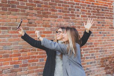 Two hipster girlfriends taking a self photo for social networks in urban city background - friendship concept. Two hipst-stock-photo