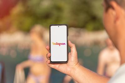 10 August 2022: A man uses the Instagram social media app on his smartphone cell phone Display Online PHOTOMONTAGE ***-stock-photo