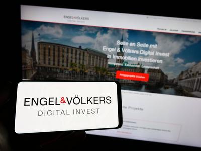 Person holding smartphone with logo of German real estate company EV Digital Invest AG on screen. Stuttgart, Germany - 0-stock-photo