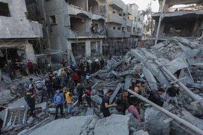 Palestinian residents of the area inspect the targeted building and surrounding structures that sustained damage after Israeli attack on Nuseirat-stock-foto