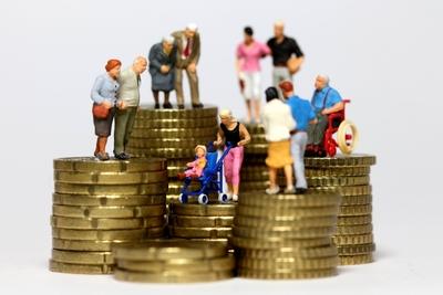 Miniatur Figuren aller Altersgruppen stehen auf Muenzstapeln-stock-photo