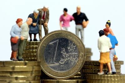 Miniatur Figuren aller Altersgruppen stehen auf Muenzstapeln-stock-photo