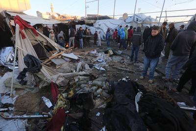 Palestinians inspect the damaged area following an Israeli attack on tents housing the displaced Palestinians in Deir al-Balah-stock-foto