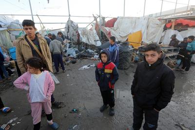 Palestinians inspect the damaged area following an Israeli attack on tents housing the displaced Palestinians in Deir al-Balah-stock-foto