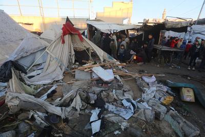 Palestinians inspect the damaged area following an Israeli attack on tents housing the displaced Palestinians in Deir al-Balah-stock-foto