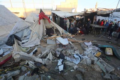 Palestinians inspect the damaged area following an Israeli attack on tents housing the displaced Palestinians in Deir al-Balah-stock-foto