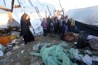Palestinians inspect the damaged area following an Israeli attack on tents housing the displaced Palestinians in Deir al-Balah-stock-foto