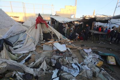 Palestinians inspect the damaged area following an Israeli attack on tents housing the displaced Palestinians in Deir al-Balah-stock-foto