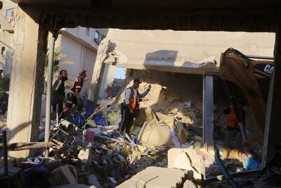 Palestinian residents and civil defense teams conduct a search and rescue operation in the Deir al-Balah-stock-photo