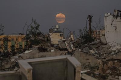 A full moon rises over destroyed buildings in the Zawaida eara in the central of Gaza Strip early-stock-foto