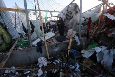 Palestinians inspect the damaged area following an Israeli attack on tents housing the displaced Palestinians in Deir al-Balah-stock-foto