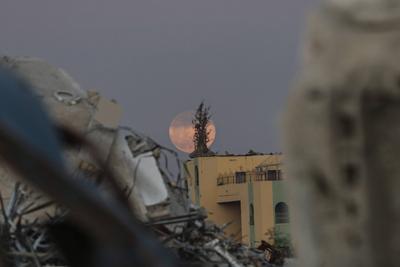 A full moon rises over destroyed buildings in the Zawaida eara in the central of Gaza Strip early-stock-foto