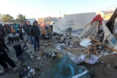 Palestinians inspect the damaged area following an Israeli attack on tents housing the displaced Palestinians in Deir al-Balah-stock-foto