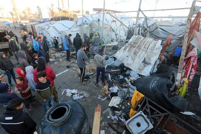 Palestinians inspect the damaged area following an Israeli attack on tents housing the displaced Palestinians in Deir al-Balah-stock-foto