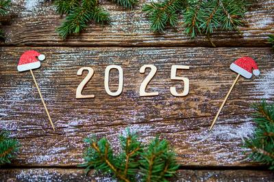 7 December 2024: The year 2025 made of wood lies on a rustic wooden table, surrounded by Christmas decorations such as d-stock-foto