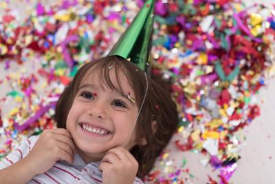 kid blowing confetti while lying on the floor Happy kid celebrating party with blowing confetti while lying on the floor-stock-foto