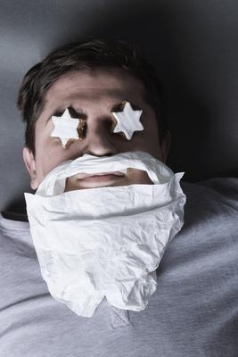Drunken Man Laying on Grey Background with Cinnamon Stars on Eyes and Handkerchief Beard *** Drunken Man Laying on Grey-stock-foto