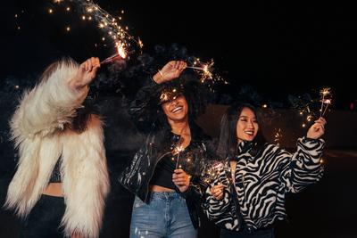 Three girls walking at night with sparklers. Young stylish women enjoying party outdoors. Three girls walking at night w-stock-foto