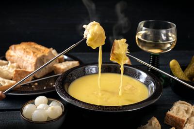 IMAGO Creative: Herbst, Kulinarische Klassiker Swiss cheese fondue with bread, pickles and wine, the festive dinner is o-stock-photo