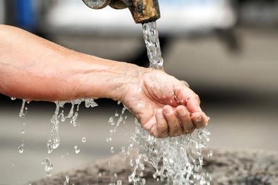 Abk?hlung am Brunnen, Frau l?sst kaltes Wasser ?ber ihr Handgelenk laufen, Hitzewelle, M?nchen, August 2024 Deutschland,-stock-photo