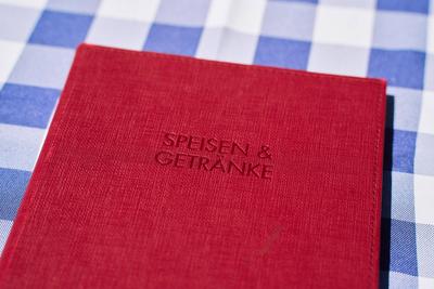 Malcesine, Lake Garda, Italy - July 20, 2024: A red menu of a restaurant on Lake Garda on an Italian checkered tableclot-stock-foto