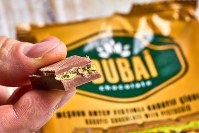 Bavaria, Germany - November 22, 2024: A man holds a piece of exclusive Dubai chocolate in front of the packaging. The ch-stock-photo