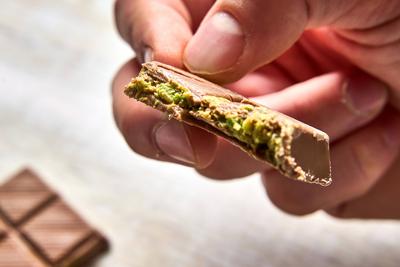 Bavaria, Germany - November 22, 2024: A man holds a single piece of the luxurious Dubai Chocolate, with pistachios and a-stock-foto