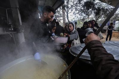 Palestinians gather to receive food cooked by a charity kitchen amid a hunger crisis as the Israel-Gaza-stock-foto