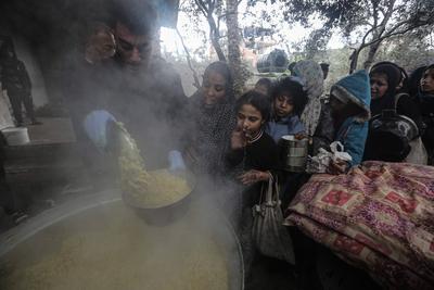 Palestinians gather to receive food cooked by a charity kitchen amid a hunger crisis as the Israel-Gaza-stock-foto