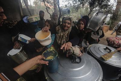 Palestinians gather to receive food cooked by a charity kitchen amid a hunger crisis as the Israel-Gaza-stock-foto