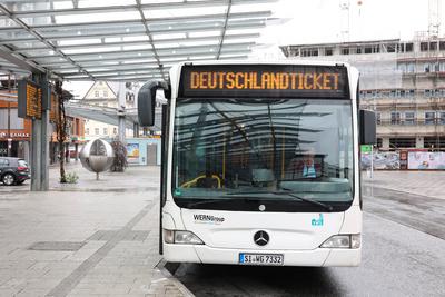 Symbolfoto zum Thema D-Ticket. Hand mit Smartphone. Im Hintergrund ein Bus mit Digitalanzeige Deutschlandticket am ZOB i-stock-foto