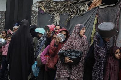 Palestinians gather to receive food cooked by a charity kitchen amid a hunger crisis as the Israel-Gaza-stock-foto