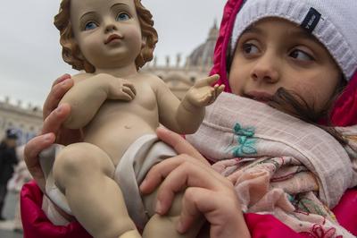 ITALY -  PEOPLE HOLD STATUETTES OF BABY JESUS IN ST PETER'S SQUARE AT  THE VATICAN  - 2024/12/22-stock-photo