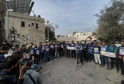 Journalists hold placards as they gather outside the Al Ahli Baptist Hospital in Gaza City to commemorate five colleagues who lost their lives in Israeli attacks on Gaza-stock-foto