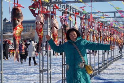 DAQING, CHINA - DECEMBER 27: A tourist poses with fish caught from the frozen Lianhuan Lake during a winter fishing even-stock-foto