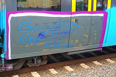 Sch?den durch Graffiti bei Bahnunternehmen Auf der Flanke eines Zuges mit Graffiti steht der Text Graffitti sind Schei?e-stock-foto