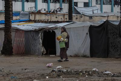 Palestinians, including children, line up to collect drinking water under rain showers inside a camp for displaced people west of Deir al-Balah-stock-foto