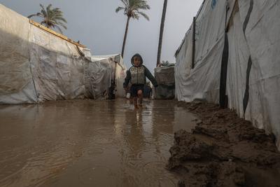 Internally displaced Palestinians walk outside their tents on a windy day west of Deir al-Balah, central Gaza Strip-stock-foto