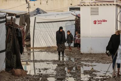 Internally displaced Palestinians walk outside their tents on a windy day west of Deir al-Balah, central Gaza Strip-stock-foto