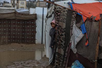 Internally displaced Palestinians walk outside their tents on a windy day west of Deir al-Balah, central Gaza Strip-stock-foto