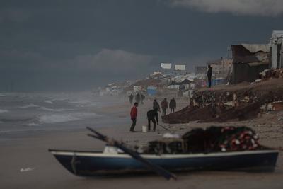 Palestinians walk on the beach during sunset on the last day of 2024 in Deir al-Balah in the central Gaza Strip, on 31 December 2024. Heavy rains in the Gaza-stock-foto