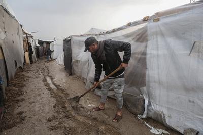 Internally displaced Palestinians walk outside their tents on a windy day west of Deir al-Balah, central Gaza Strip-stock-foto