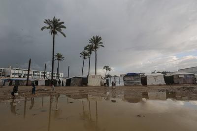 Internally displaced Palestinians walk outside their tents on a windy day west of Deir al-Balah, central Gaza Strip-stock-foto
